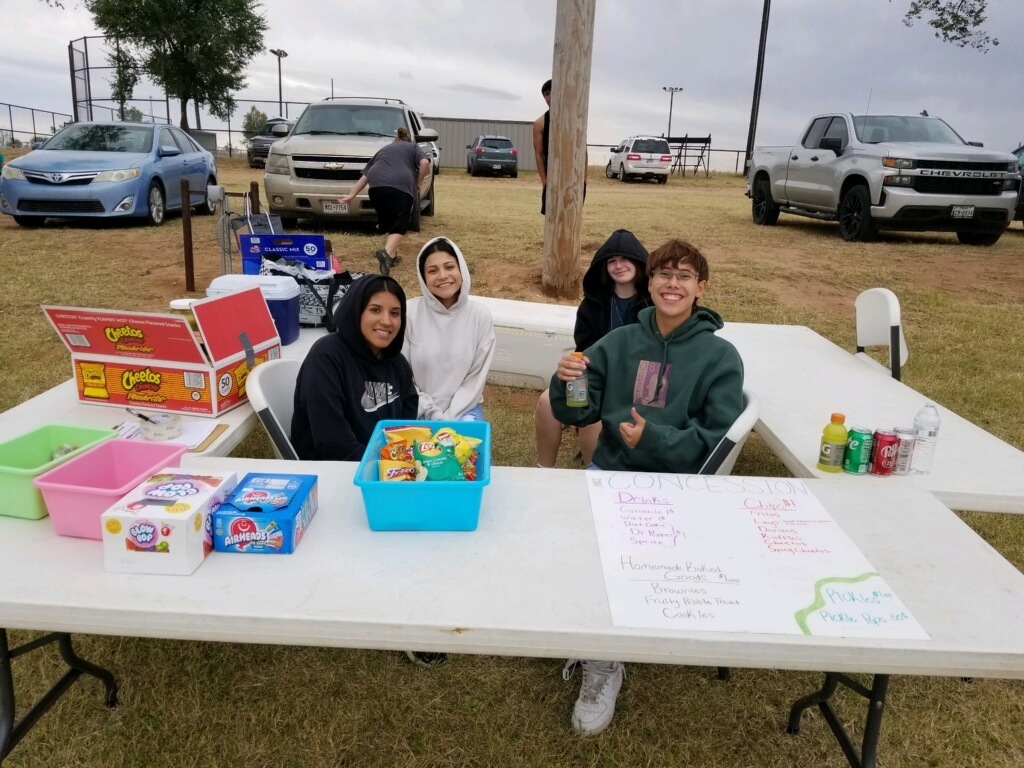 Students at a table outdoors selling concessions